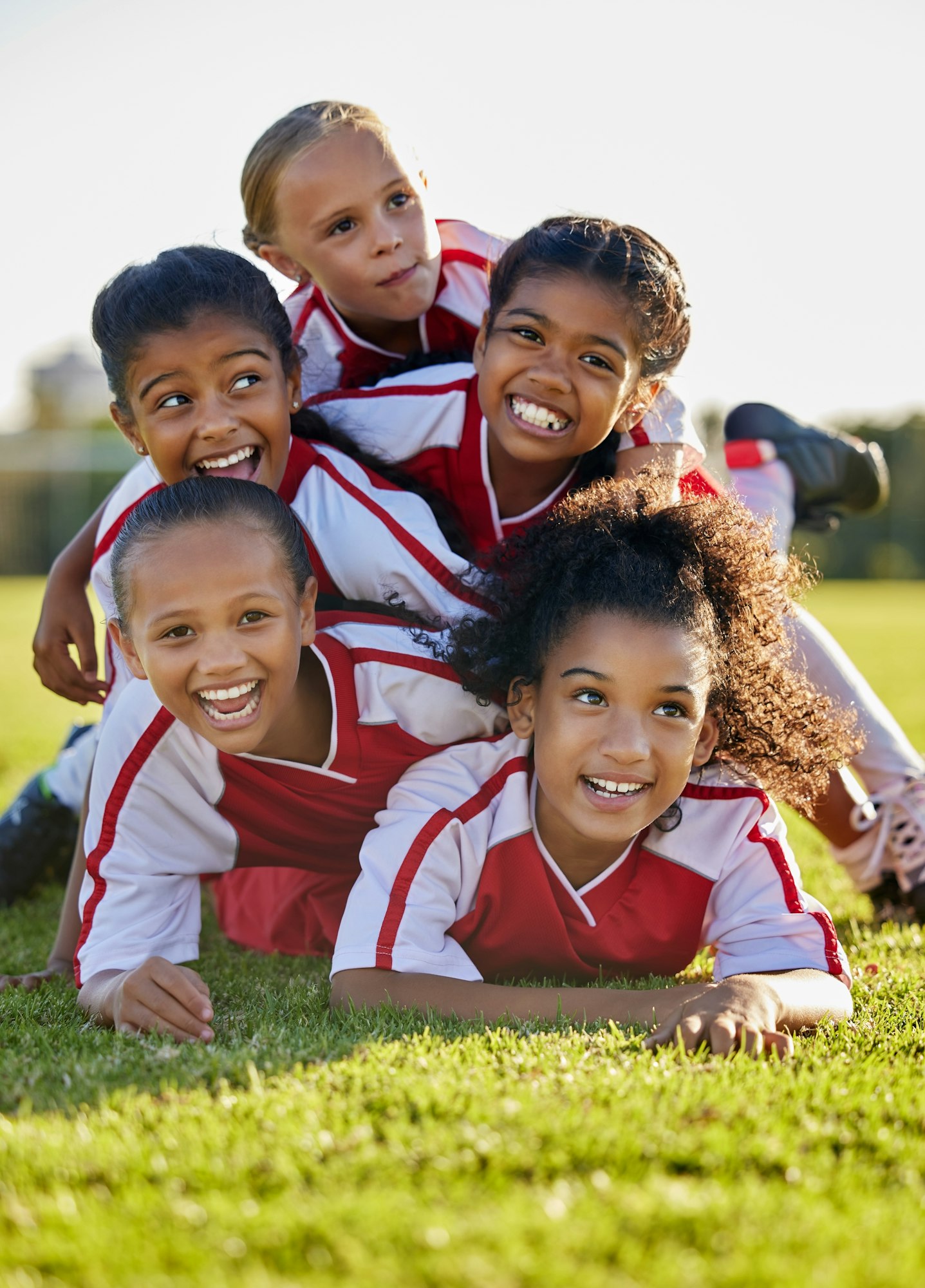 Team, children and happy on field in sports after win in match, game or competition. Girl, smile an